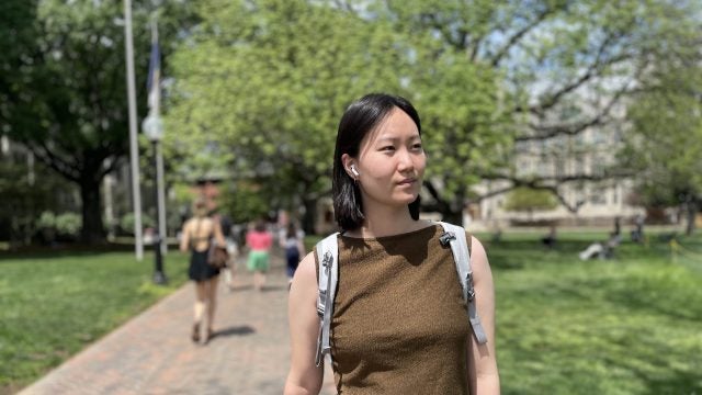 A student walks across campus with AirPods in her ears